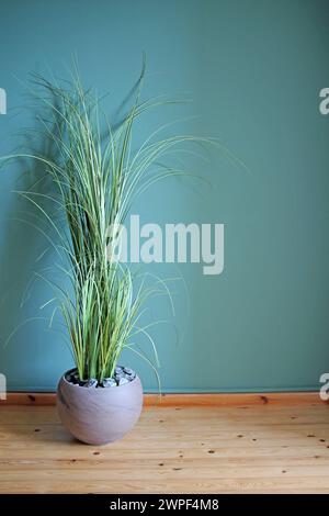 Artificial home plant on a green wall background. Space for your text. Stock Photo