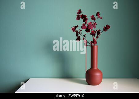 Blooming branch in a modern ceramic vase on a white table. Oriental style desiogn. Space for your text. Stock Photo