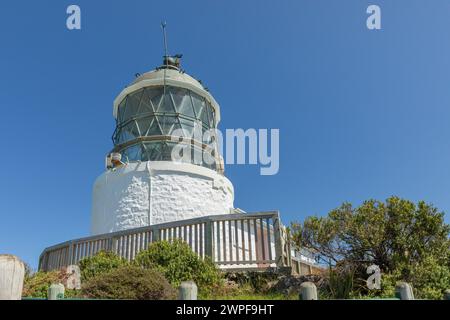 The 10-metre Nugget Point lighthouse, off the Southern Scenic Route, was first lit in 1870. Surrounded by rocky islets or nuggets, it was was automate Stock Photo