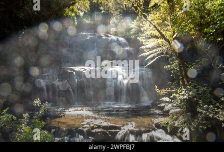 Spray from the Purakaunui Falls, off the Southern Scenic Route on the South Island of New Zealand, plays tricks with the light. Stock Photo