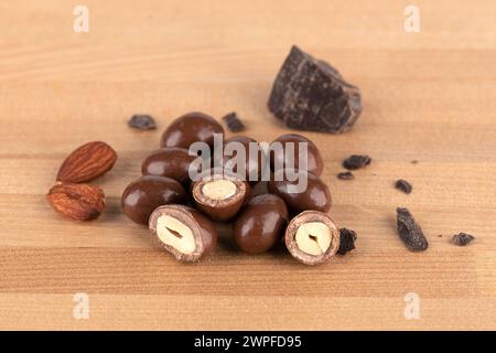 Chunks of dark chocolate and dark chocolate covered nuts on a wooden surface. Copy space. Stock Photo