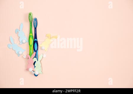 Happy Easter dental clinic greeting card, toothbrushes and bunnies on a peach color background Stock Photo