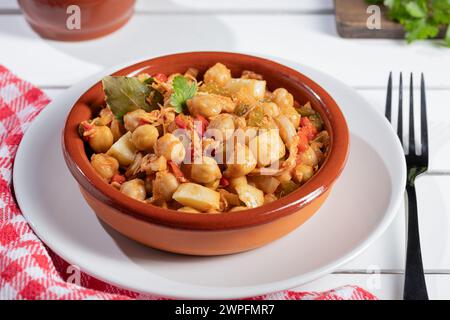 Close up. Ropa vieja, typical Canarian dish of chickpeas stew on earthenware casserole on white table. Stock Photo