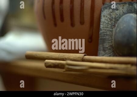 Close-up of a ceramic piece with craft tools and cinnamon sticks, showing the texture and detail of the manual work. Stock Photo