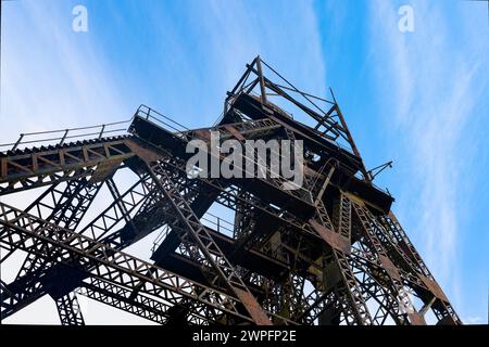 winding gear of coal mining colliery looking up from below against a blue sky, Astley Green Lancashire UK Stock Photo