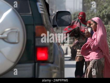 Poor woman beggar along with child begs for alms at a roadside on the eve of International Women Day at GT Road in Peshawar on Thursday, March 7, 2024. Stock Photo