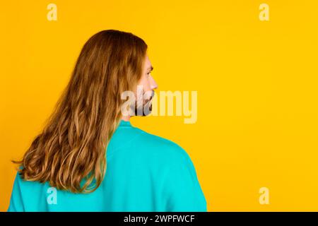 Rear profile photo of focused young man curly long hairstyle look empty space isolated on yellow color background Stock Photo