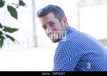 a good-looking handsome male model smiling at the camera while looking back over his shoulder inside with sunglasses on his head. Stock Photo