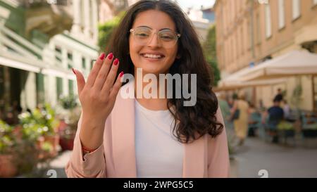 Portrait young cheerful wide smiling teeth pleasant expression Indian Arabian multiracial woman businesswoman lady female calling come here beckons Stock Photo