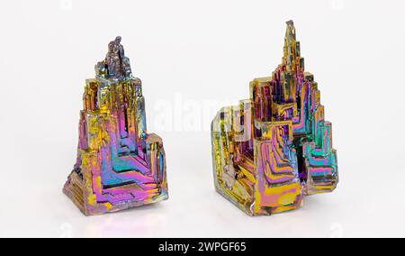 Beautiful colored brittle bismuth hopper crystals with stairstep structure on white background. Two heavy metal pieces of diamagnetic chemical element. Stock Photo