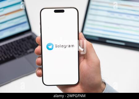 PRAGUE, CZECH REPUBLIC - JANUARY 21 2024: Telegram logo on the screen of smartphone in mans hand on the workplace background.  Stock Photo