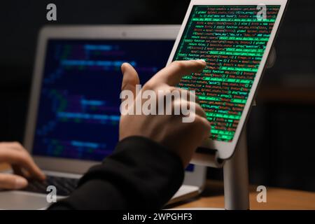 Hacker using tablet computer in dark room, closeup Stock Photo