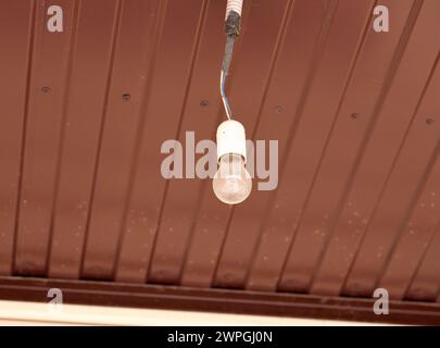 A dusty light bulb hanging from a ceiling Stock Photo
