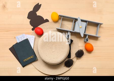Hat with toy plane, passports and Easter decor on light wooden background. Holiday travel composition Stock Photo