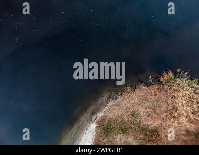 Aerial look down view on river dark water surface with green reeds on riverbanks. Autumnal river in Ukraine Stock Photo