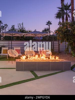 Outdoor backyard patio at night with a fireplace and chairs in Palm Springs, California Stock Photo