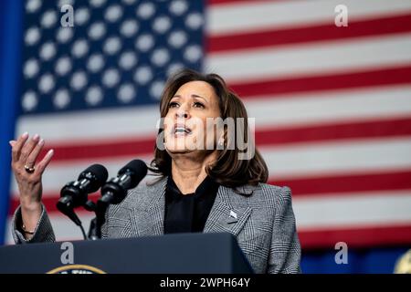 Vice President Kamala Harris gives a speech while gesturing with her right hand standing at a podium in front of an American flag in the background. Stock Photo