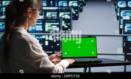 Proficient system administrator in server farm housing high end rackmounts capable of quickly and efficiently performing complex computations and data analysis, using mockup laptop to prevent crashes Stock Photo