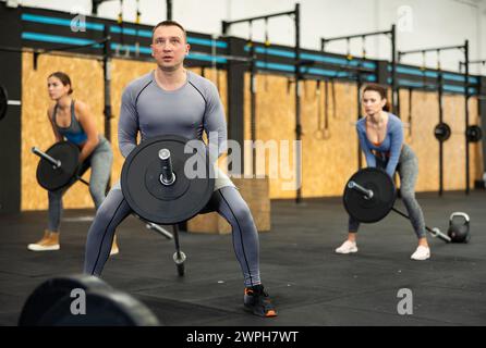 Concentrated middle-aged man performing T-Bar row at gym Stock Photo