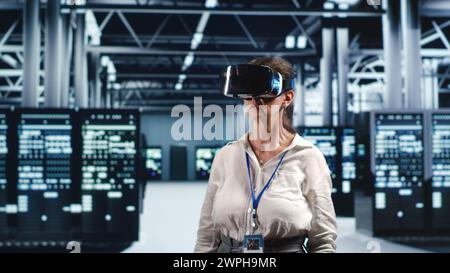 Aged IT admin in modern server room wearing virtual reality headset, performing racks maintenance. Trained specialist using vr glasses in high tech workspace to do checkup on hardware Stock Photo