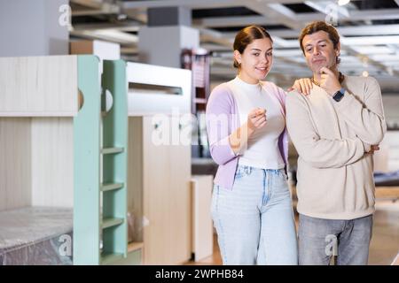 Happy man and woman choosing kids furniture in furniture showroom Stock Photo