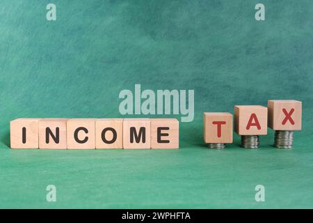 Income tax increase concept. Word in wooden blocks with increasing stack of coins. Stock Photo