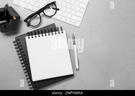Flat lay composition with notebooks, keyboard and glasses on light grey table Stock Photo