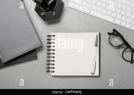 Flat lay composition with notebooks, keyboard and glasses on light grey table Stock Photo