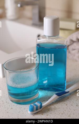 Fresh mouthwash in bottle, glass and dental floss on countertop, closeup Stock Photo
