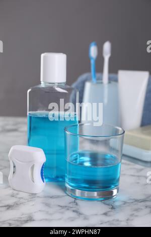 Fresh mouthwash in bottle, glass and dental floss on white marble table, closeup Stock Photo