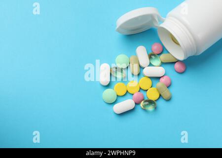 White bottle and different vitamin pills on light blue background, above view. Space for text Stock Photo