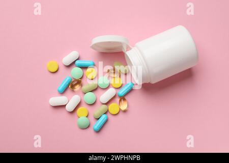 White bottle and different vitamin pills on pink background, top view Stock Photo