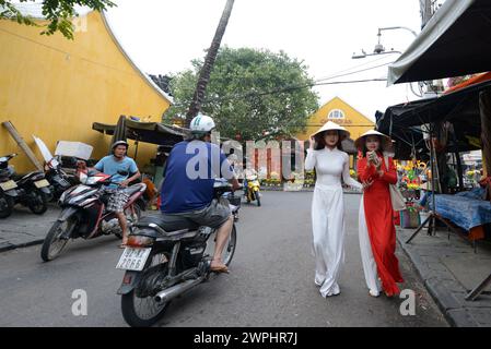 Tourist wearing Vietnamese clothes and hats in the old city of Hoi An, Vietnam. Stock Photo