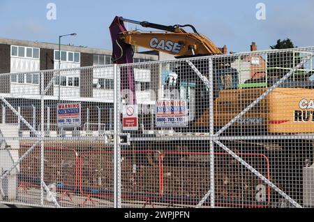 Tracked excavator behind fence with warning signs on construction site, radcliffe regeneration scheme, near bury, greater manchester uk Stock Photo