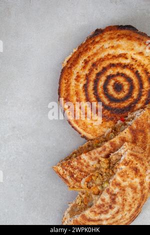 Jaffle, an old school toasted sandwich, filled with savory mince. Grey backdrop, copy space Stock Photo