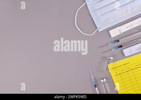 Virus antigen test, vaccine passport, medical face masks, vaccine vials with syringes on gray background with copy space Stock Photo