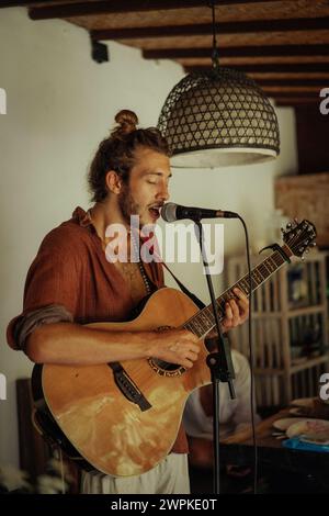 Young man musician plays the guitar and sings into a microphone. Stock Photo