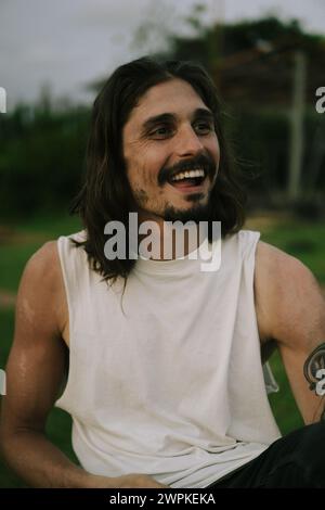 Portrait of smiling young man with long brown hair and dark eyes. Stock Photo