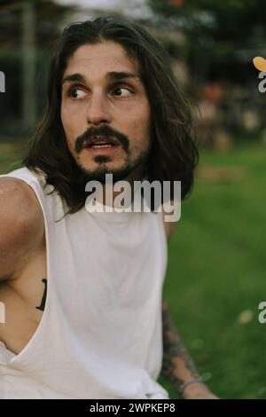 Portrait of smiling young man with long brown hair and dark eyes. Stock Photo