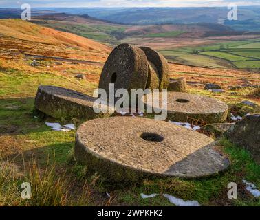Evening light on abandoned mIllstones below Stanage Edge in the Derbyshire Peak District UK looking towards the Derwent valley Stock Photo