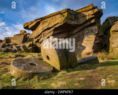 Evening light on abandoned mIllstones below Stanage Edge in the Derbyshire Peak District UK looking towards the Derwent valley Stock Photo