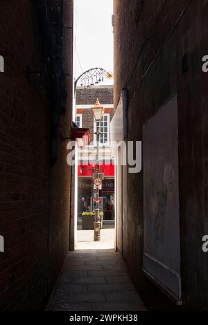 Narrow and claustrophobic, probably very old, access alley path between two shop building / buildings in Banbury, Oxfordshire. UK. (134) Stock Photo