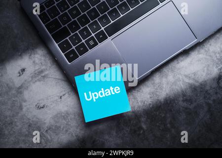 Blue adhesive note on laptop with the word update written on it. Software upgrade concept with empty space for use. Stock Photo