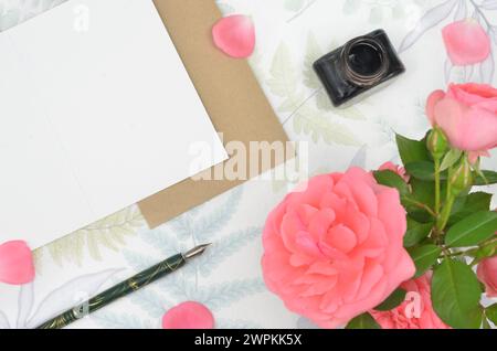 White sheet of paper on a table, decorated with pink flowers, calligraphy pen and ink. Stock Photo