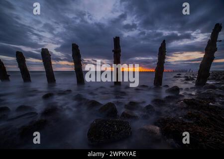 Storm clouds gather over the Irish Sea, worn sea defences from South Walney at sunset from the Cumbrian Coast, Cumbria, England, United Kingdom, Europ Stock Photo