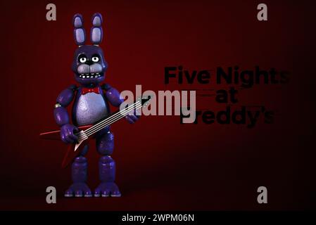 Figure of Bonnie character of the videogames,movies and books Five Nights at Freddy's and logo over red background. Illustrative editorial Stock Photo