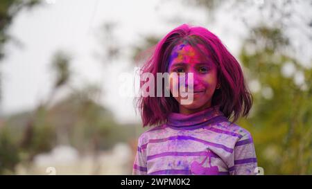 Kid blowing holi colour powder from hand during Holi festival celebration - Concept of young kids having fun by playing holi during festive Stock Photo