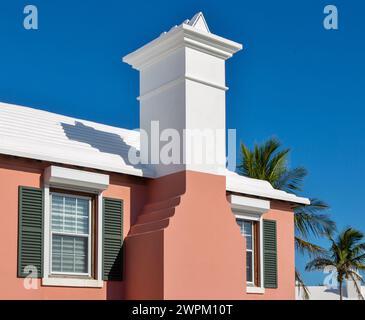 Typical Bermuda architecture, building painted in pastel colours, with white stepped roof designed to catch rainwater for storage in underground tanks Stock Photo