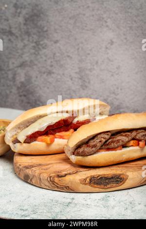 Turkish bread with kashar sausage and meatballs on the presentation board. Local name ekmek arası sucuk ve köfte Stock Photo