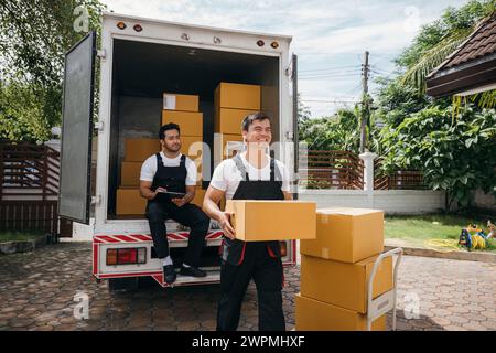 Moving service workers unload boxes from a van showing teamwork and cooperation. Delivery men in Stock Photo